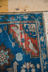 Antique Caucasian rug detail: stylized bird motif with geometric blue and red patterns.