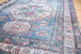 Vintage Caucasian carpet with distressed low pile and geometric blue and red patterns.