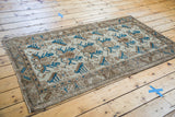 Distressed Mehraban rug corner, featuring textured trefoil and serrated leaf motifs in ivory, bronze, indigo.