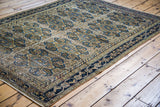 Distressed antique Feraghan rug with repeating blue paisley and tan medallion patterns.