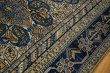 Antique Feraghan rug with a distressed tan field, blue paisley motifs, and rich navy geometric borders.