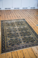 Antique Feraghan rug corner displaying intricate navy border and time-softened multi-medallion field motifs.