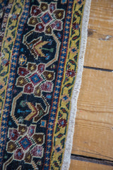 Distressed antique Feraghan rug's multi-medallion pattern with germinating flower motif and white fringe.