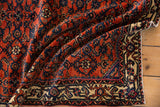 Folded antique Engelas rug pile with intricate Herati design, rich rust, indigo, and beige borders.