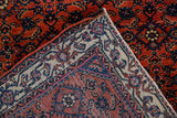 Corner of an antique Persian Engelas rug revealing woven foundation, fringe, and gem-tone herati pattern.