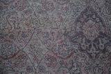 Muted red, blue, and grey curvilinear motifs on distressed Turkish Sivas carpet pile.