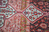 Geometric ivory medallion detail with red floral motifs against an abrashed charcoal and mauve vintage Malayer pile.