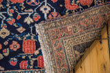 Folded corner of vintage Afshar rug showing deep dark blue floral pile and geometric woven foundation.