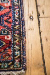 Woven edge and pile detail of a vintage Afshar rug with cinnabar red and deep blue florals.