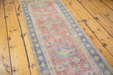 Faded red, beige, blue lotus and vine motifs on distressed vintage Oushak runner.