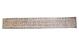 Distressed Oushak rug runner with muted coral, blue lotus flower vines, and geometric borders.