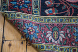 Detailed view of brilliant floral patterns and woven structure on a folded antique Bakhtiari rug.