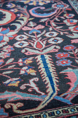 Expressive curvilinear floral motifs in brilliant red, blue, and cream on the antique Bakhtiari carpet.