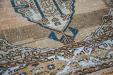 Detail of vintage Sivas rug with distressed texture, blue lozenge medallion, and abrashed coral field.
