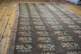 Repeating peach and sage blossoming floral motifs on a distressed charcoal Konya carpet.