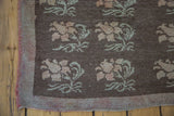 Distressed Konya carpet corner showing faded blossoming floral motifs on a charcoal field.