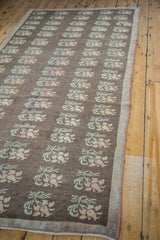 Repeating pale blossoming floral motifs on charcoal brown distressed Konya carpet.