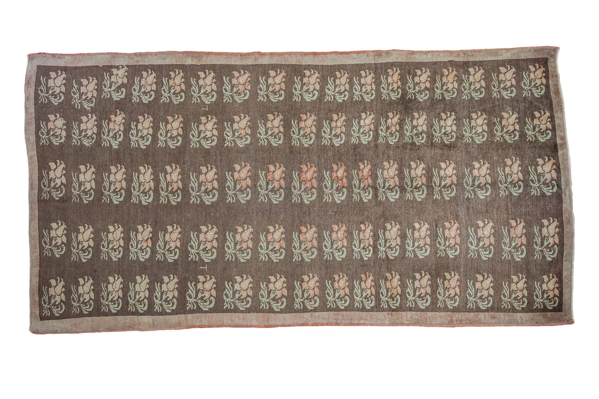 Distressed Konya carpet featuring repeating pastel floral motifs on a charcoal field, 5x9.5.