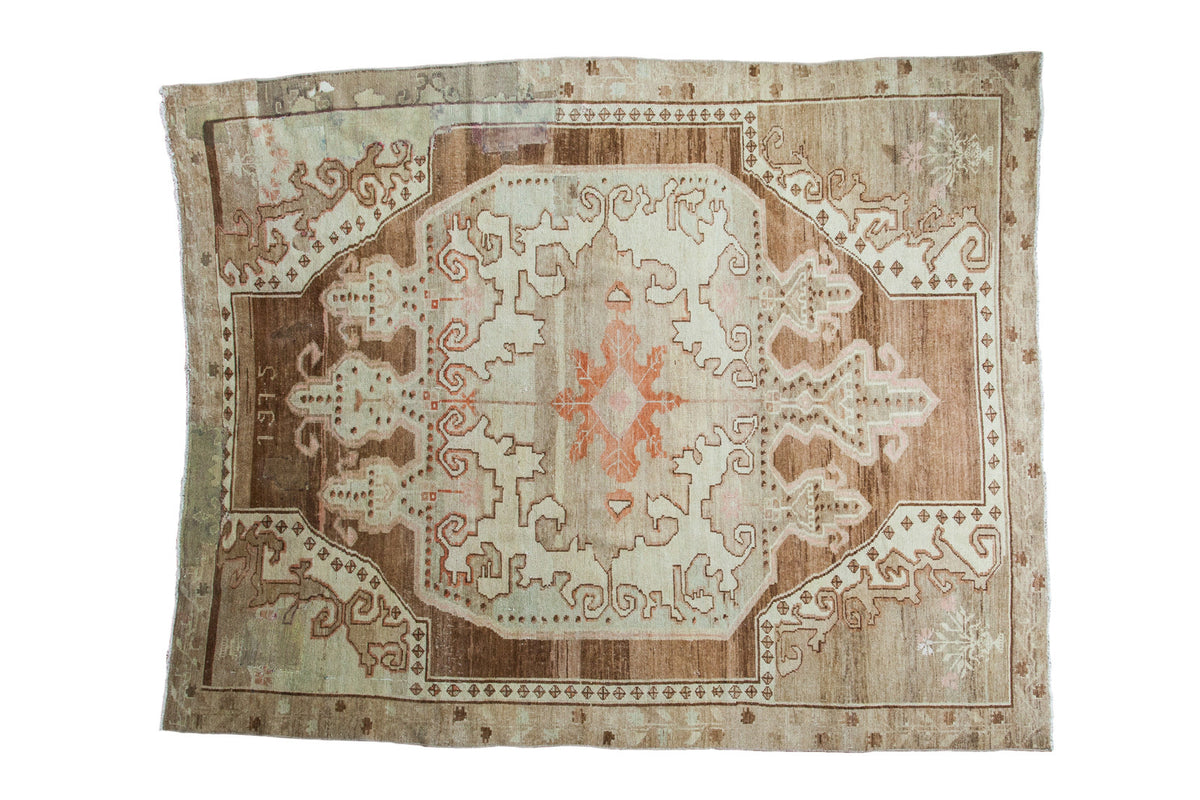 Distressed Oushak carpet displaying an orange rust medallion, plush pile, and aged patina.