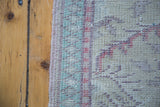 Distressed vintage Turkish Oushak runner's edge detail with pastel lattice pattern.