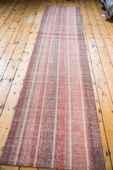 Flat woven Kilim texture showing vertical rose red and wine burgundy stripe variations.