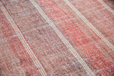 Flat woven Kilim rug texture with rose red, wine burgundy striations, and thin white stripes.