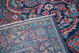 Vintage Mahal rug corner folded, revealing dense hand-knotting, foundation, and meandering leaf border.