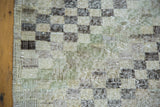 Distressed Oushak rug checker motif, showcasing worn texture in ivory, charcoal, moss green.