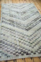 Modern distressed Oushak rug featuring geometric checker pattern and worn texture.