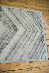 Distressed Oushak rug edge, highlighting checker motif, worn texture, and neutral tones.