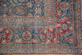 Antique Tabriz rug corner close-up, revealing intricate indigo blue Herati motif and rusty red accents.