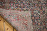 Antique Persian Tabriz rug, folded corner revealing intricate Herati motif, brilliant indigo, rusty red, and woven foundation.