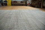 Distressed Oushak carpet surface with subtle intricate medallions in beige and grey.