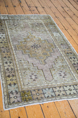 Distressed vintage Oushak rug's geometric medallion in softened bronze, celadon green, and mauve.