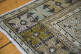 Distressed Oushak rug close-up, highlighting softened bronze, celadon, and blue geometric motifs.