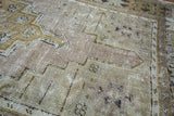 Distressed Oushak rug detail, faded pile with softened bronze and celadon geometric lines.