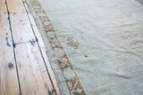 Detail of a distressed vintage Oushak runner showing its bronze leaf border.