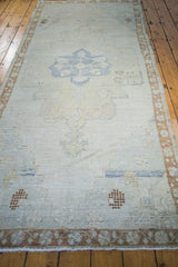 Bottom edge of distressed Oushak rug, showing blanched silvery gray pile with bronze leaf border.