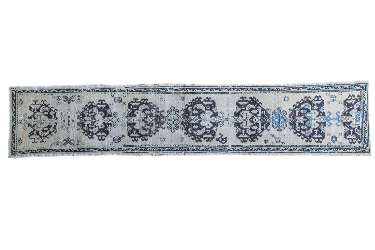 Distressed vintage Oushak runner with charcoal, silver, and blue geometric patterns.