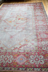 Distressed Oushak carpet corner with brick red border, ivory, orange floral and lantern motifs.