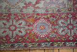 Distressed Oushak rug edge, brick red border, and ivory-grey stylized floral designs.