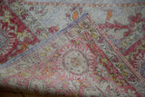 Folded distressed Oushak carpet showcasing worn red, yellow pile and its hand-woven back.
