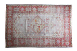 Distressed vintage Oushak carpet with faded ivory and grey medallion, framed by brick red floral borders.