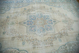 Textural detail of blanched aqua and blue/green palmette floral motifs on a distressed Oushak carpet.