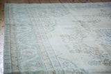 Blanched aqua meandering leaf and palmettes border on a distressed Oushak rug.