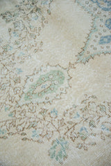 Distressed Oushak rug texture showing blanched aqua and blue-green floral motifs.