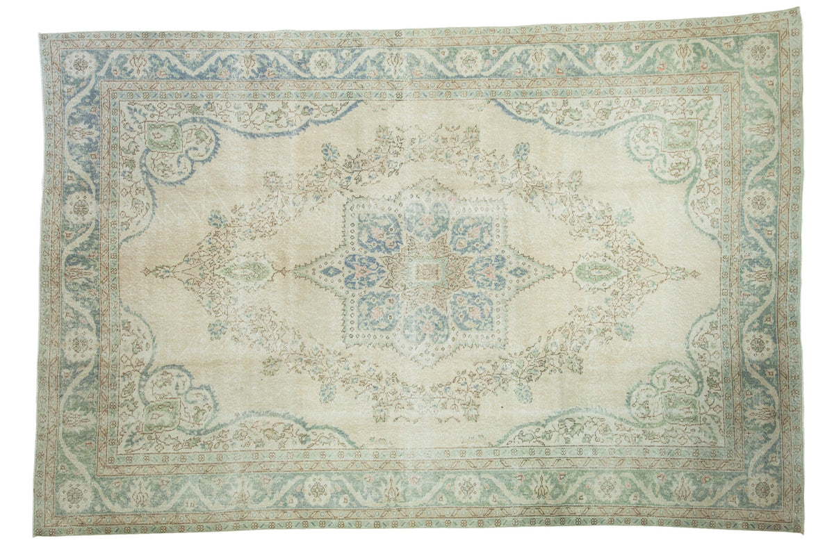 Distressed Oushak rug with large central medallion, blanched aqua palmettes, and blue-green border.