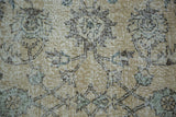 Softened ivory and earth tone faded floral motifs on distressed Oushak pile.