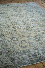 Angled view of a vintage distressed Oushak rug, faded ivory, earth tones, allover pattern.