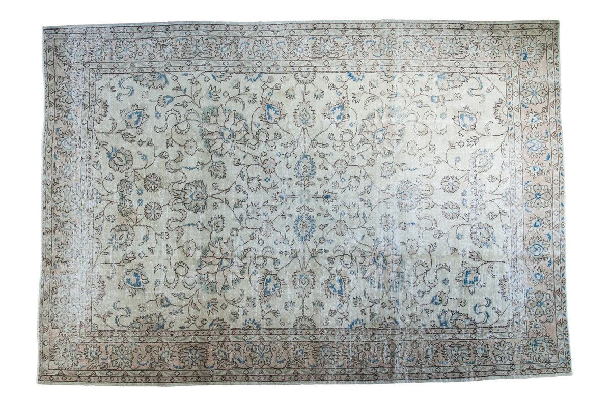 Distressed Oushak Carpet with softened faded ivory, earth tones, and blue floral design.